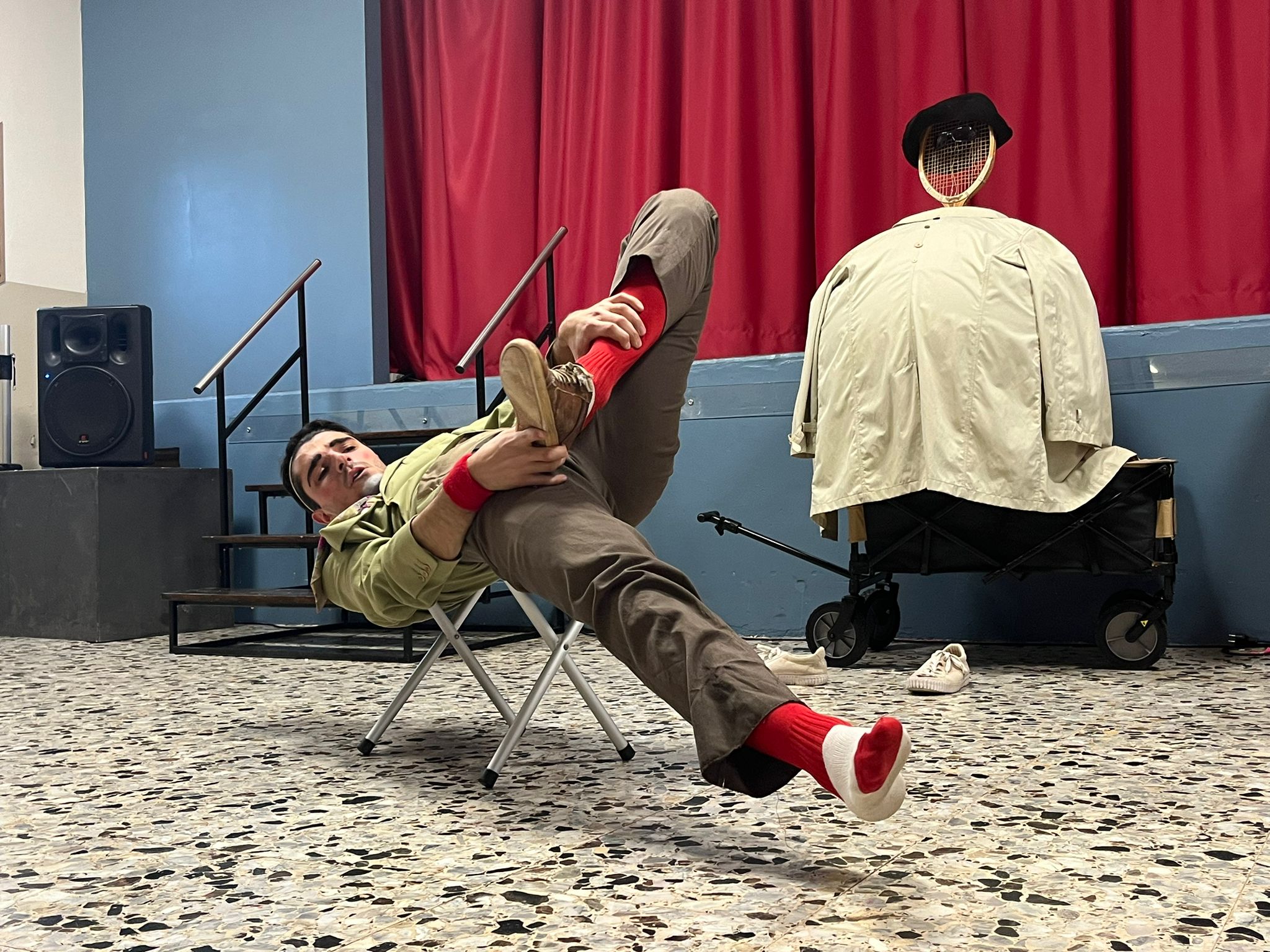 Un clown seduto in maniera strana su uno sgabellino.